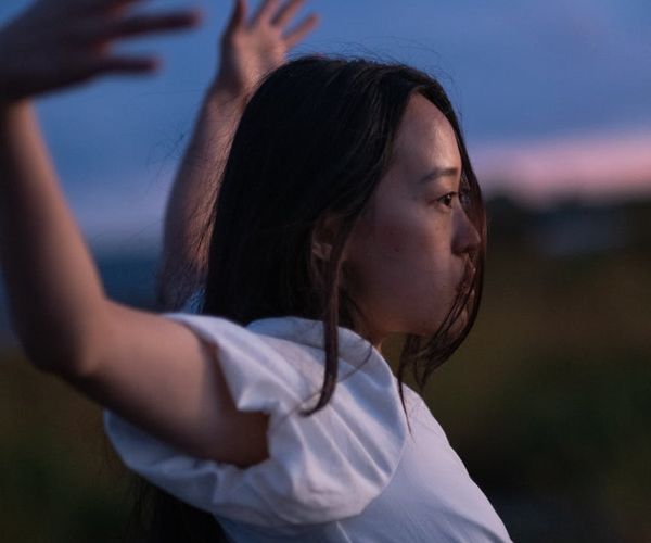 Person stretching peacefully outdoors with a serene natural background.